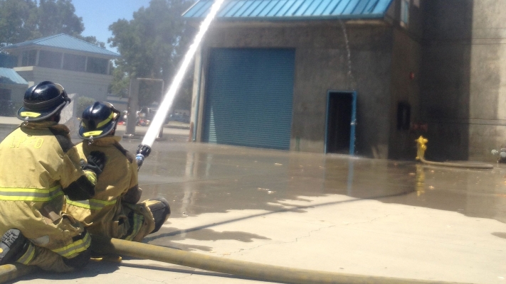 Two trainees shooting water from a firehose